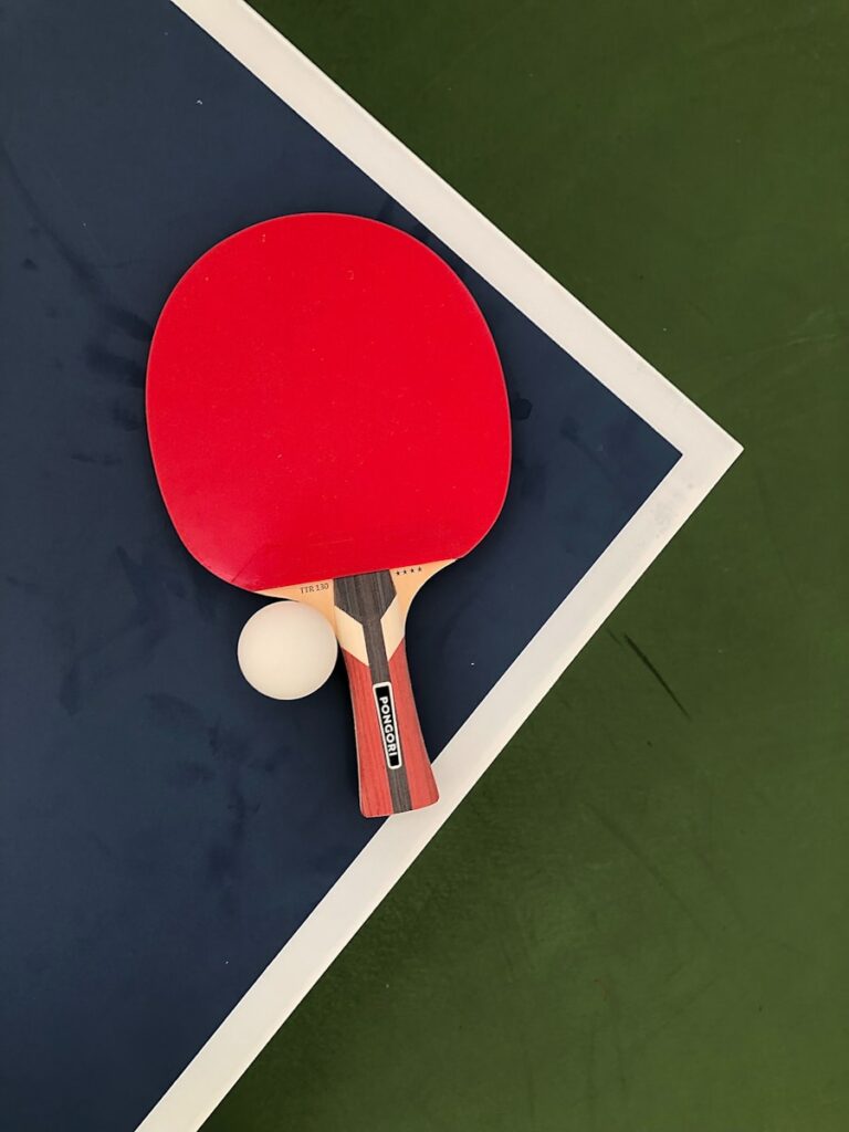 A ping pong paddle and a ping pong ball on a blue and green